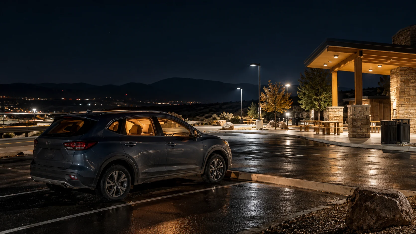 Car parked at a lit highway rest stop at night